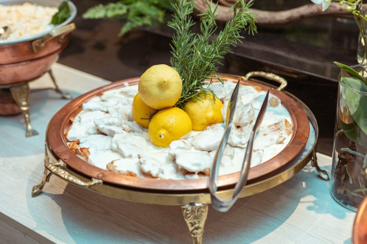 A delectable creamy dish garnished with lemons and rosemary on a luxury buffet setting.