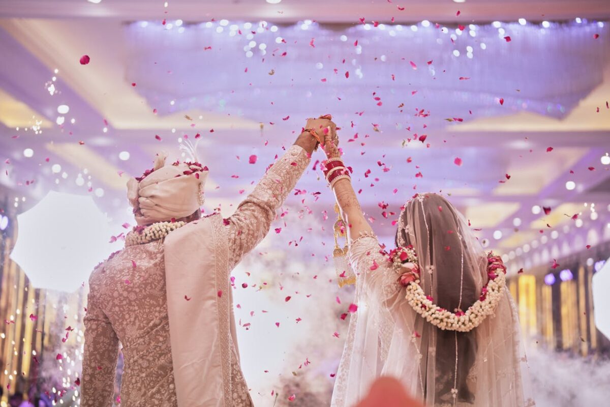 Capturing a blissful moment as a couple celebrates their Indian wedding with flower petals showered indoors.